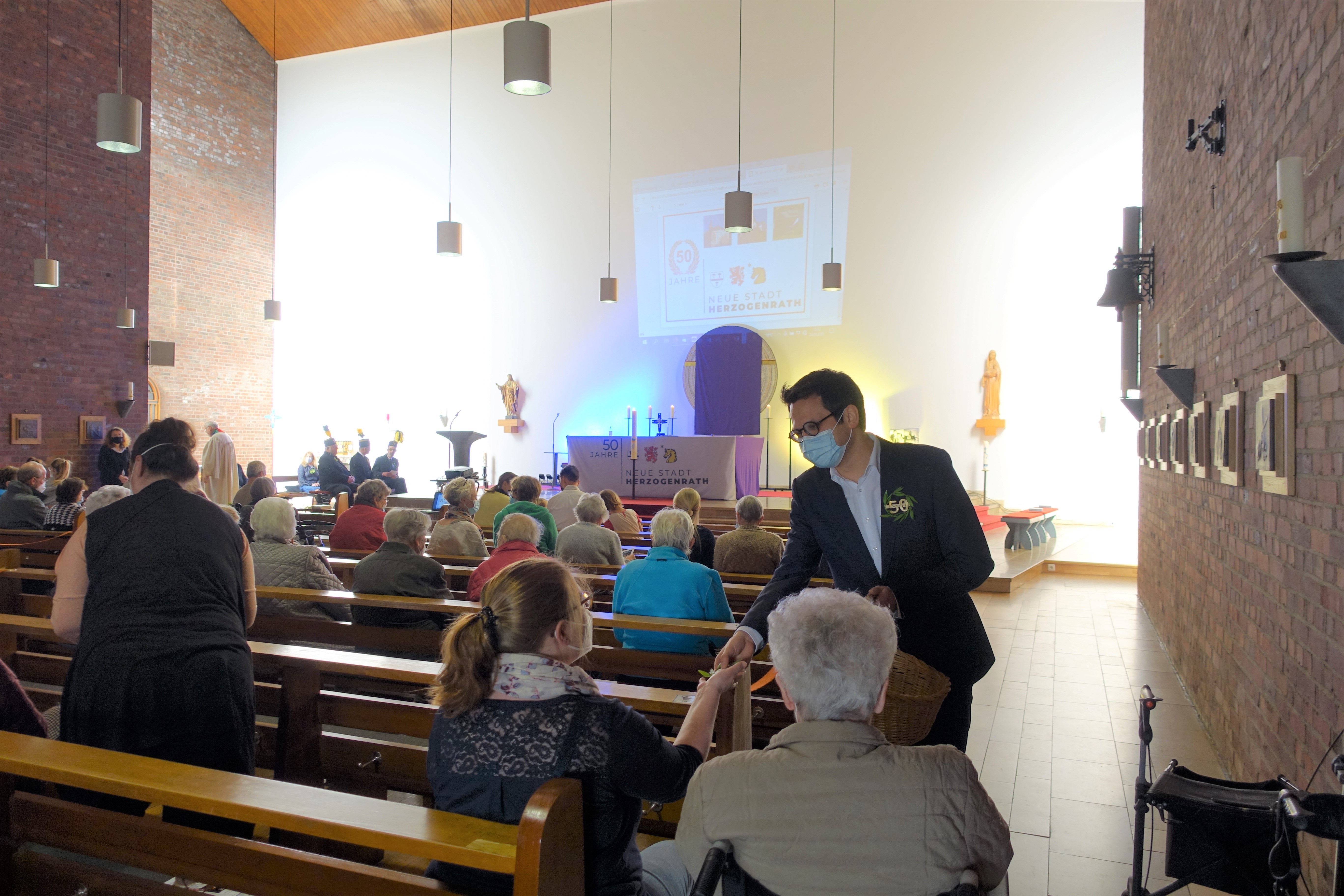 Das Bild zeigt Bürgermeister Dr. Benjamin Fadavian bei der Verteilung von 50-Jahre Lorbeerkränzen an die Gottesdiensteilnehmer*innen