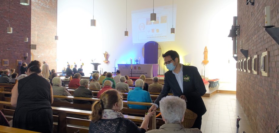 Das Bild zeigt Bürgermeister Dr. Benjamin Fadavian bei der Verteilung von 50-Jahre Lorbeerkränzen an die Gottesdiensteilnehmer*innen