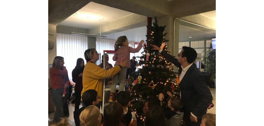 Herzogenraths Bürgermeister Dr. Benjamin Fadavian und Kinder der Kita Lydia-Gemeinde schmücken den Weihnachtsbaum im Herzogenrather Rathausfoyer