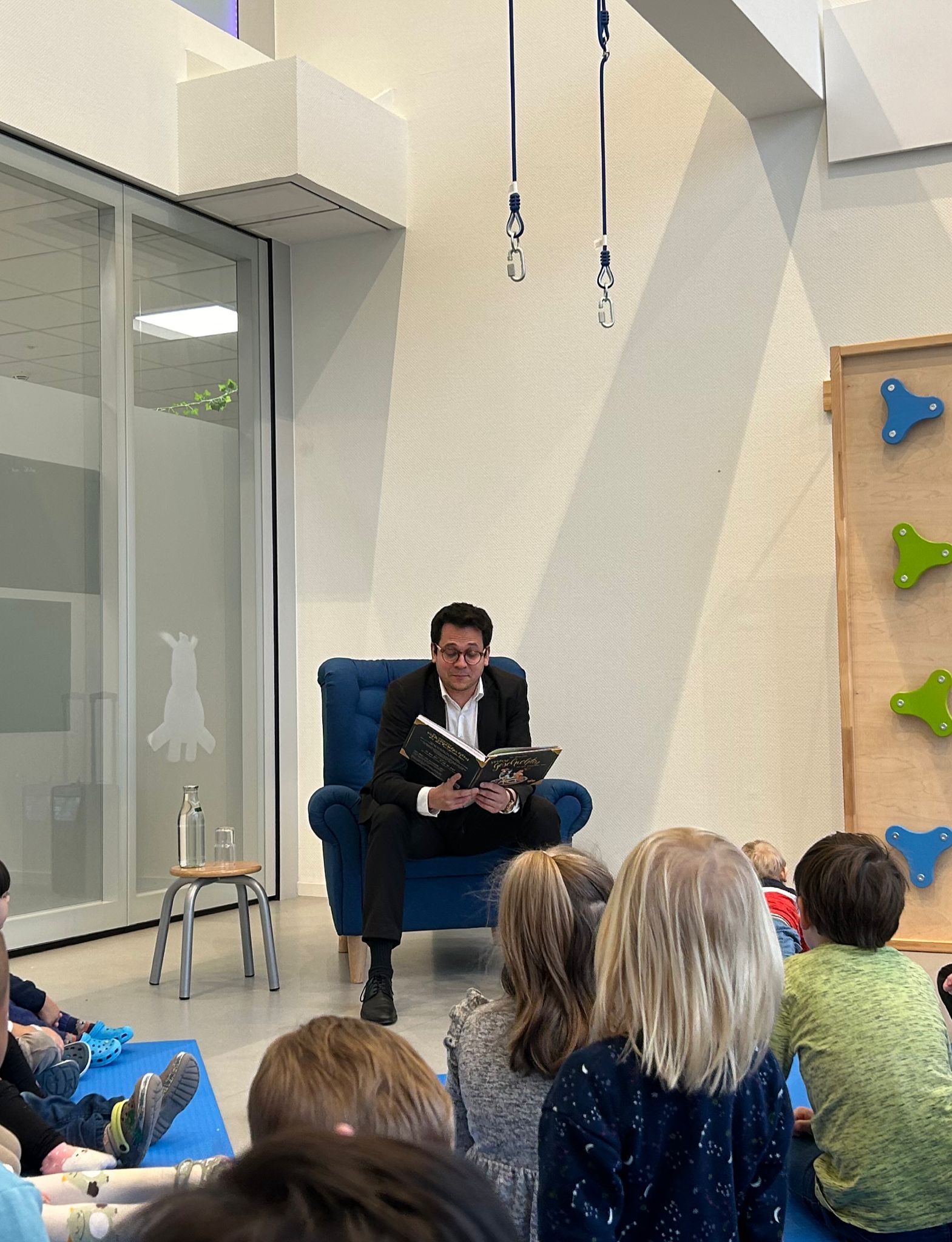 Bürgermeister Dr. Fadavian beim Vorlesen der Geschichte in einem Stuhl, vor ihm sitzend die Kinder der Kita Safari