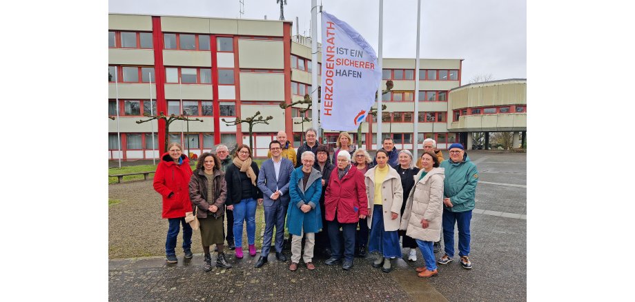 Gruppenbild der Mitglieder des Runden Tisches für Flüchtlingsarbeit, Migration und Integration beim Hissen der neuen Flagge