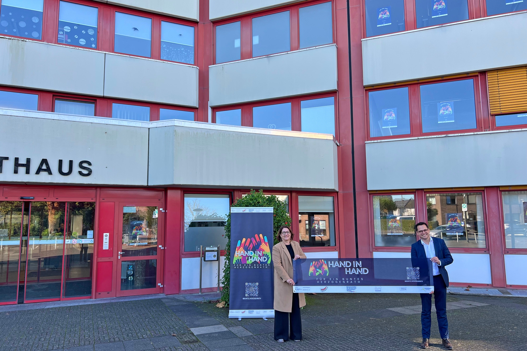 Renate Wallraff (Beigeordnete für Soziales, Bildung und Familie) und Bürgermeister Dr. Benjamin Fadavian präsentieren die Motive der "Hand-in-Hand"-Aktion.