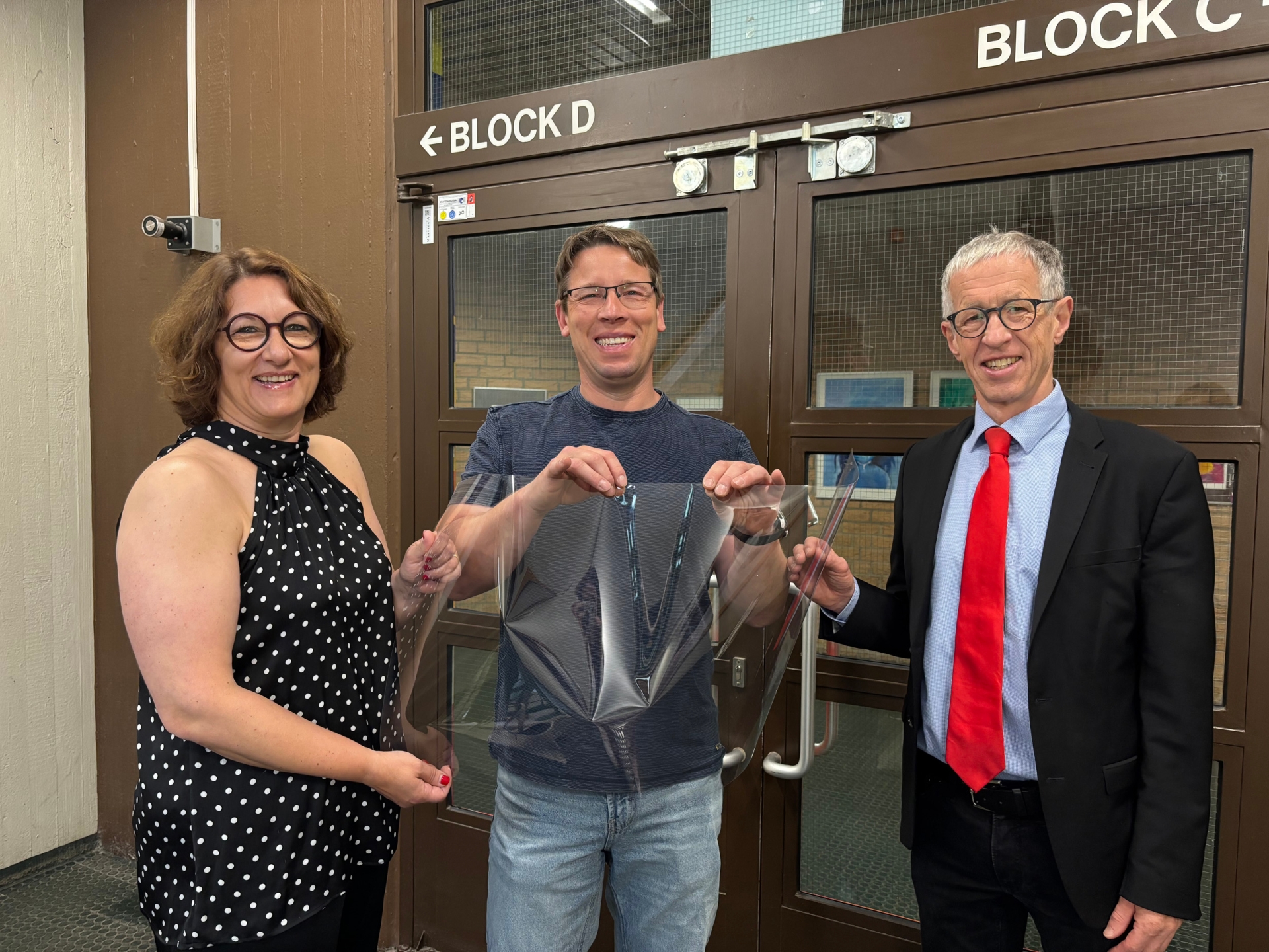 Renate Wallraff (Beigeordnete für Soziales, Bildung und Familie), Björn Topa und Michael Höbig (Schulleiter des Gymnasiums Herzogenrath) mit der neuen Splitterschutzfolie