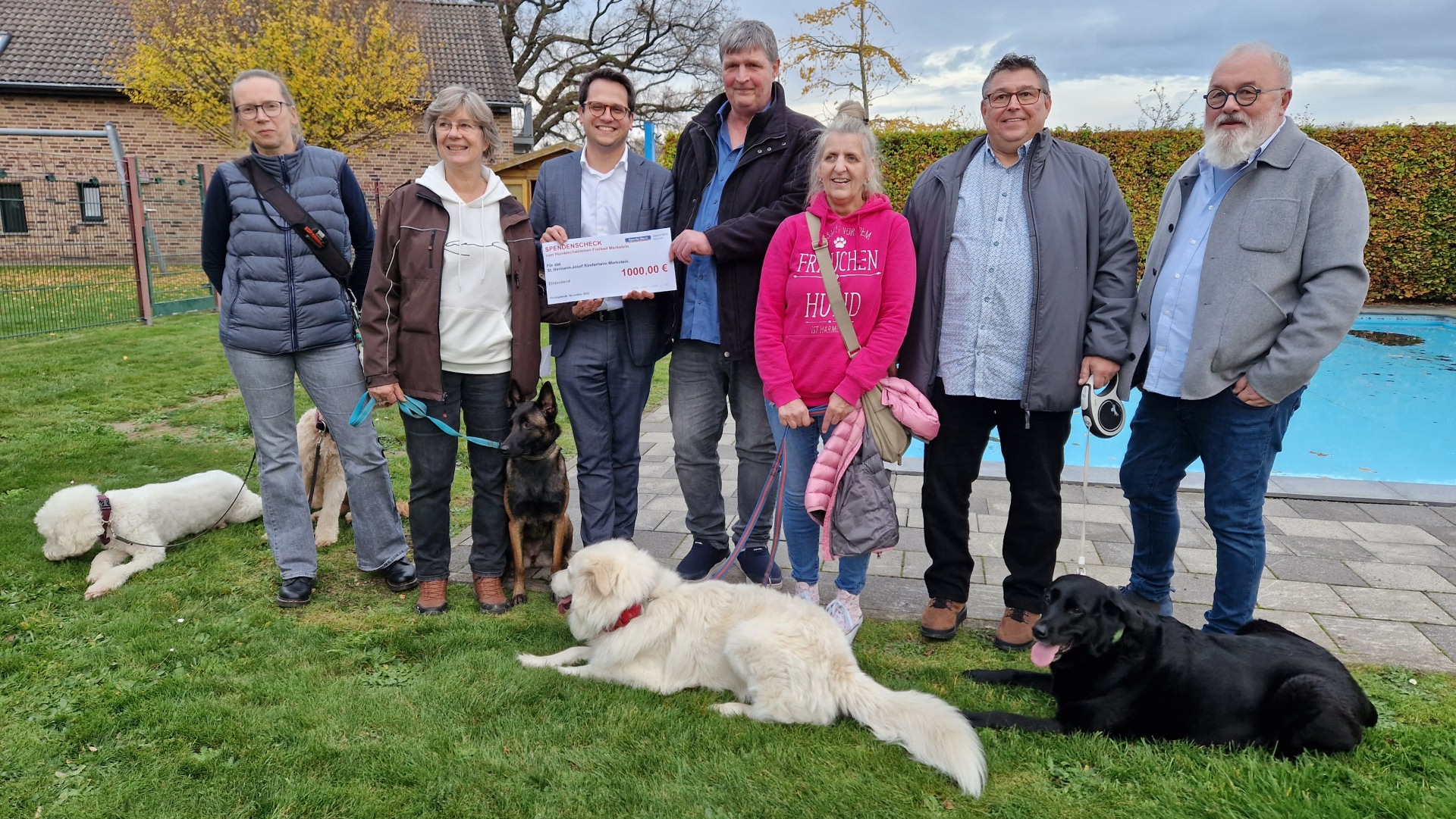 Die Organisatorin des Hundeschwimmens Tina Reiß (2.v.l.), den Bürgermeister Dr. Benjamin Fadavian (3.v.l.) mit dem Leiter des Kinderheims St. Hermann-Josef, Lothar Mauer, (M.) und  Dieter Forth, Geschäftsführer des Kinderheim-Trägers SkF Alsdorf e.V. (1.v.r.) sowie weitere Teilnehmende des Hundeschwimmens mit ihren Tieren.