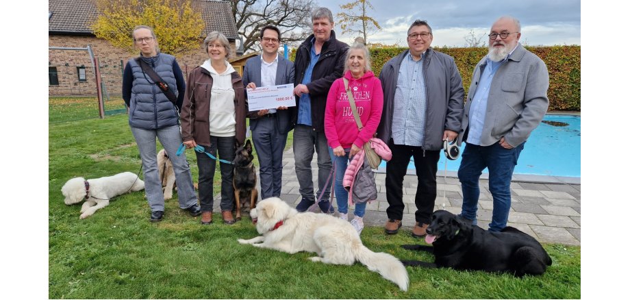 Die Organisatorin des Hundeschwimmens Tina Reiß (2.v.l.), den Bürgermeister Dr. Benjamin Fadavian (3.v.l.) mit dem Leiter des Kinderheims St. Hermann-Josef, Lothar Mauer, (M.) und  Dieter Forth, Geschäftsführer des Kinderheim-Trägers SkF Alsdorf e.V. (1.v.r.) sowie weitere Teilnehmende des Hundeschwimmens mit ihren Tieren.