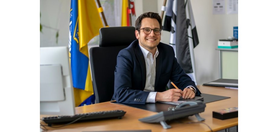 Auf dem Fot sieht man den Bürgermeister Dr. Benjamin Fadavian, der an seinem Schreibtisch sitzt.