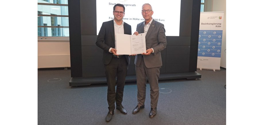 Bürgermeister Dr. Benjamin Fadavian mit Regierungspräsident Gregor Lange bei der Übergabe des Bescheids in Köln Bürgermeister Dr. Benjamin Fadavian mit Regierungspräsident Gregor Lange bei der Übergabe des Bescheids in Köln