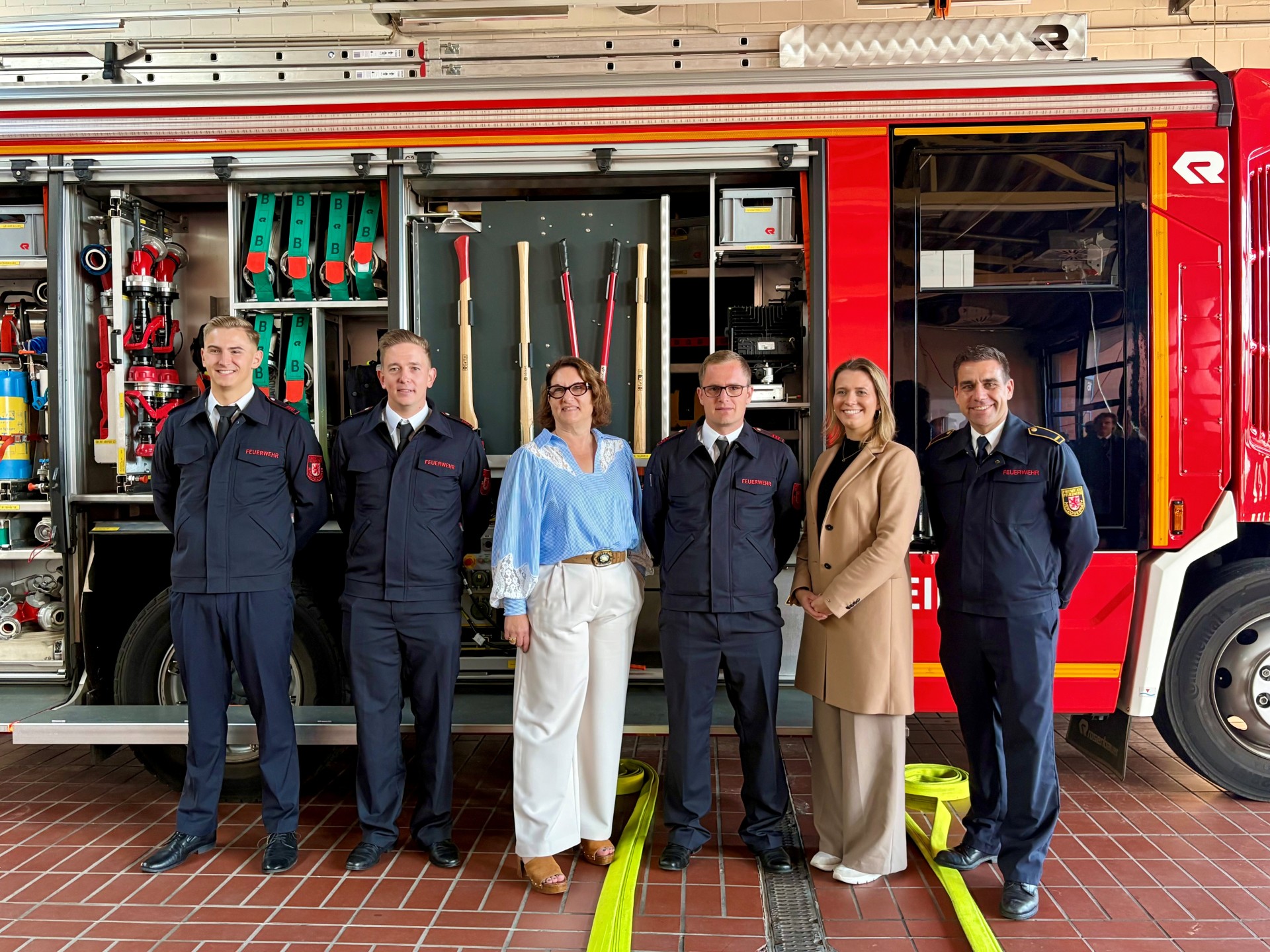 Neue Brandmeister für die Feuerwehr Herzogenrath - Jens Ruben Graß, Luca Scheidt und Simon Braun mit Beigeordnete Renate Wallraff, Julia Oidtman (Personalwesen), Hr. Schütte Leiter der Feuerwehr Herzogenrath vor einem offenen Löschfahrzeug in der Garage der Feuerwache