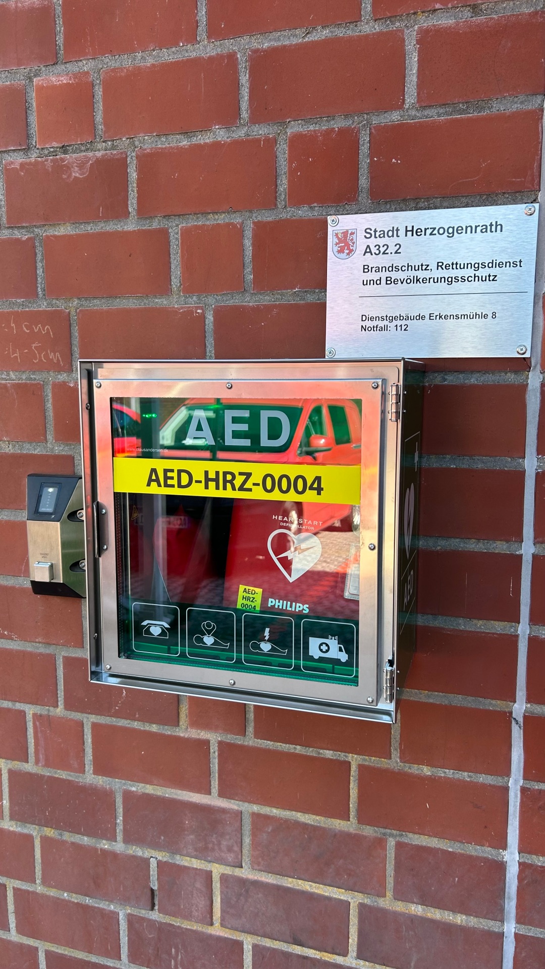 Defibrillator an der Feuer- und Rettungswache Herzogenrath - am Eingang der Wache an der Wand