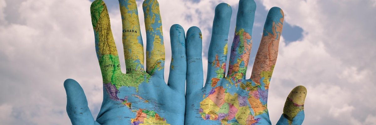 Hände-zwei Handinnenflächen bemalt mit Weltkugel vor Wolkenhintergrund