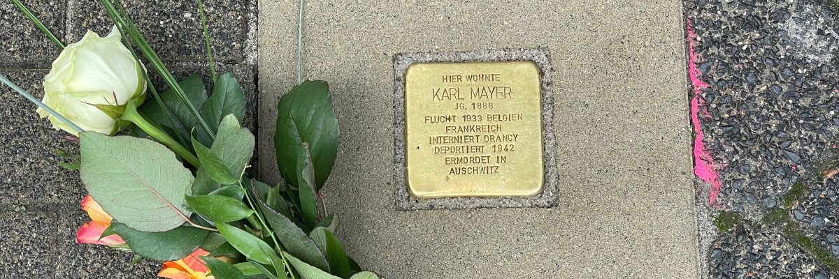 Ein Stolperstein mit niedergelegten Blumen