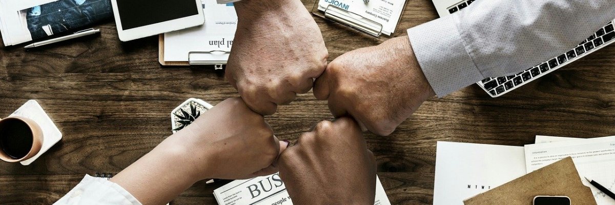 Verwaltung-Banner-verschiedene Fäuste über Schreibtisch sternförmig zusammenkommend