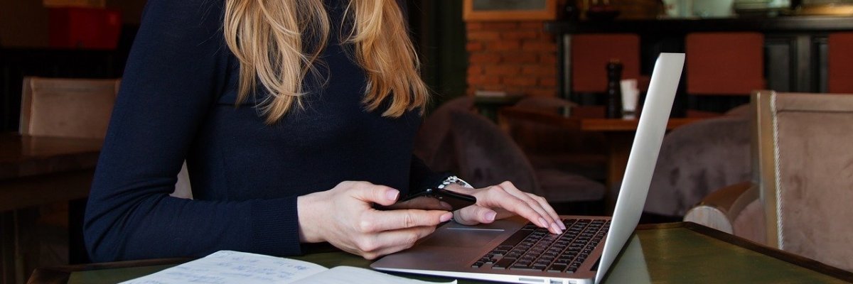 Frau am Labtop mit Handy Frau am Labtop mit Handy
