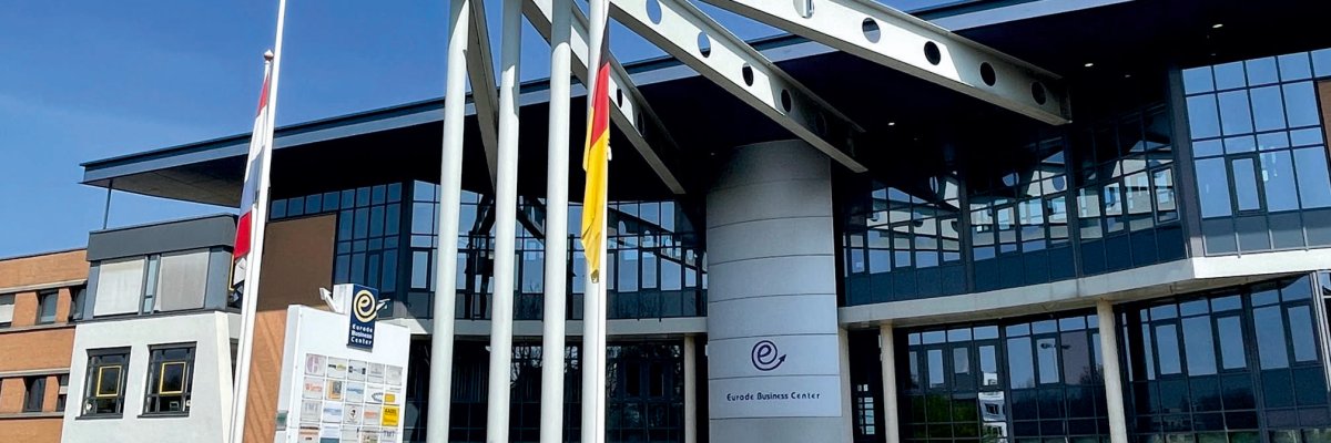 Foto: Vordere Seite des EBC Gebäudes Das Foto zeit den vorderen Bereich des EBC Gebäudes, welches sich durch die Glasfront und seine vorstehenden Stahlträger auszeichnen