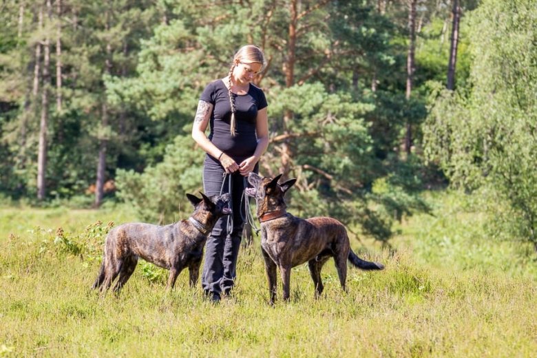 Jil Meyer mit zwei Hunden auf einer Wiese im Wald