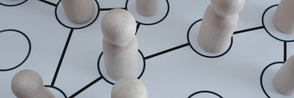 Das Foto zeigt Spielfiguren aus Holz die mit gezeichneten Linien miteinander verbunden sind